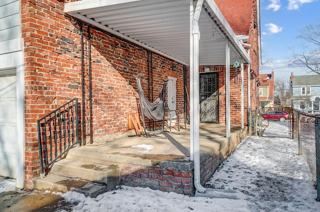 snow covered patio with fence and a carport