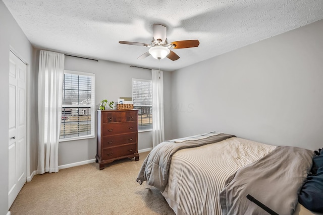 bedroom featuring light colored carpet, ceiling fan, a textured ceiling, and baseboards