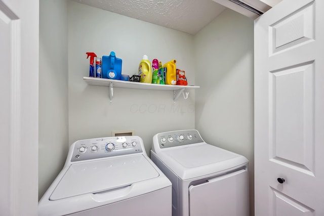 clothes washing area with laundry area, a textured ceiling, and washing machine and clothes dryer