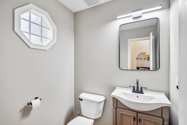 bathroom with toilet, vanity, and visible vents