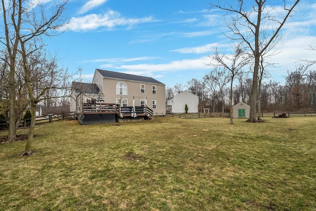 view of yard featuring an outbuilding, fence, a deck, and a storage unit