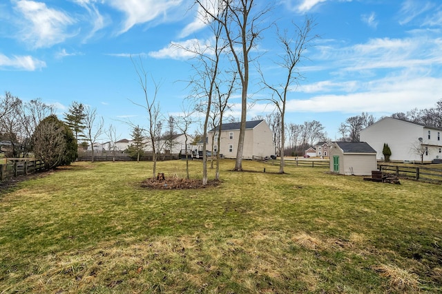 view of yard featuring a residential view, a fenced backyard, an outdoor structure, and a storage unit