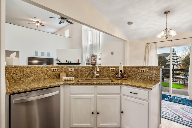 kitchen featuring a sink, white cabinets, vaulted ceiling, stainless steel dishwasher, and dark stone counters