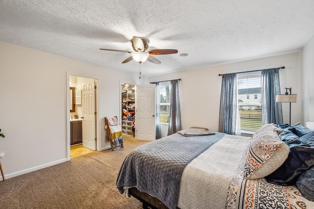 bedroom featuring light colored carpet, multiple windows, a spacious closet, and baseboards