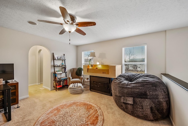 living area with arched walkways, ceiling fan, a textured ceiling, and baseboards