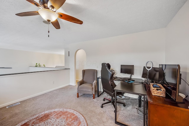 office area with baseboards, visible vents, arched walkways, a textured ceiling, and carpet floors