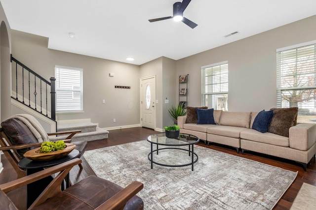 living room with baseboards, visible vents, a ceiling fan, dark wood-style flooring, and stairs