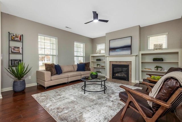 living area with visible vents, dark wood-type flooring, ceiling fan, a tile fireplace, and baseboards