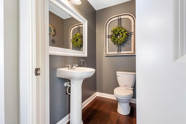 half bathroom with toilet, baseboards, and wood finished floors