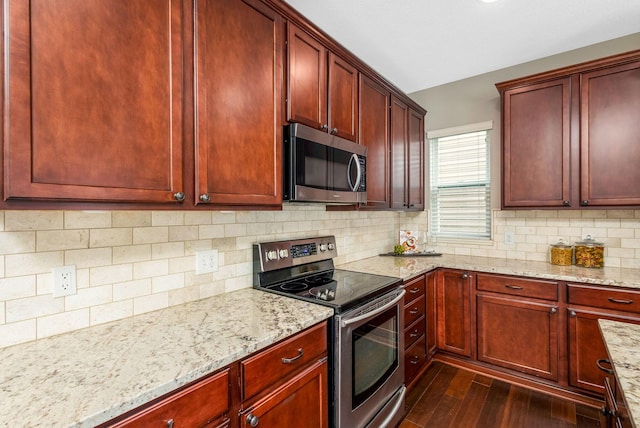 kitchen featuring stainless steel appliances, backsplash, dark wood-type flooring, dark brown cabinets, and light stone countertops