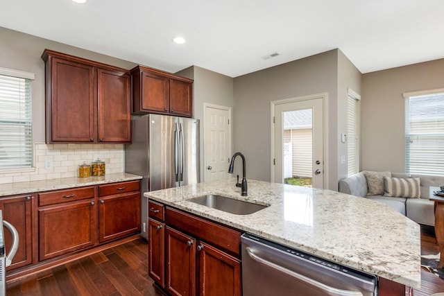 kitchen featuring a center island with sink, visible vents, dark wood-type flooring, stainless steel appliances, and a sink