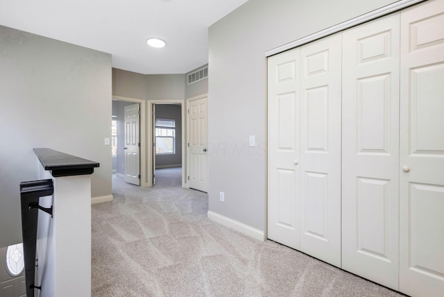 hall featuring an upstairs landing, light colored carpet, visible vents, and baseboards