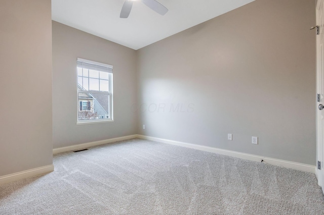 empty room featuring ceiling fan, carpet floors, visible vents, and baseboards