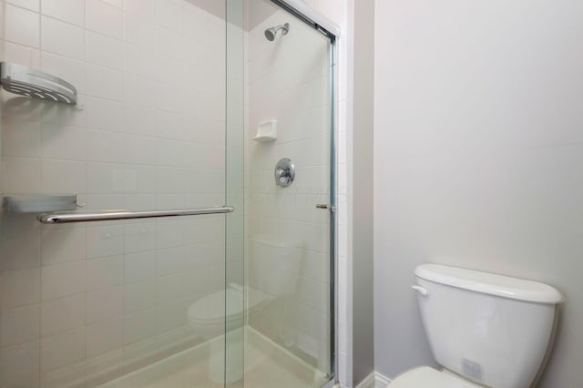 full bathroom featuring a stall shower and toilet