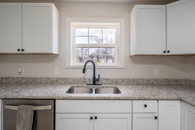 kitchen with light stone counters, dishwasher, white cabinetry, and a sink