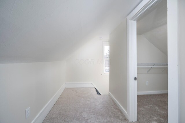 additional living space featuring baseboards, carpet, and vaulted ceiling