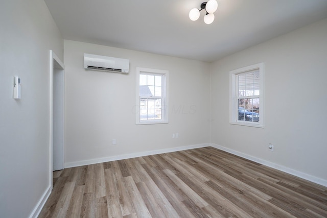 unfurnished room featuring an AC wall unit, wood finished floors, and baseboards