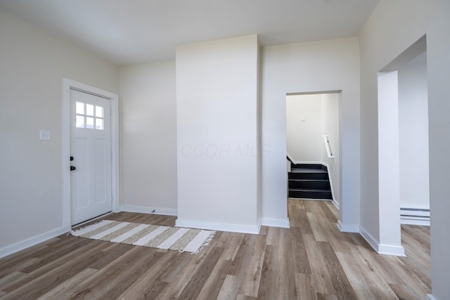 entryway featuring baseboards, stairs, and light wood-style floors