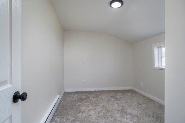 empty room featuring baseboards, lofted ceiling, baseboard heating, and carpet flooring