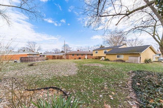 back of property with a yard, fence, and stucco siding