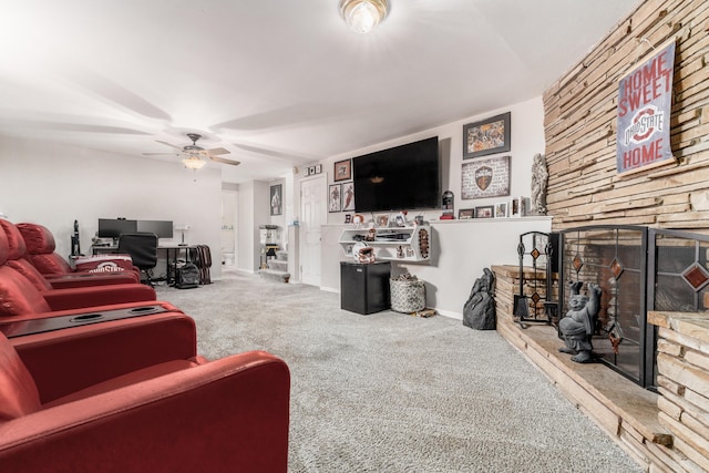 carpeted living room with a large fireplace and a ceiling fan