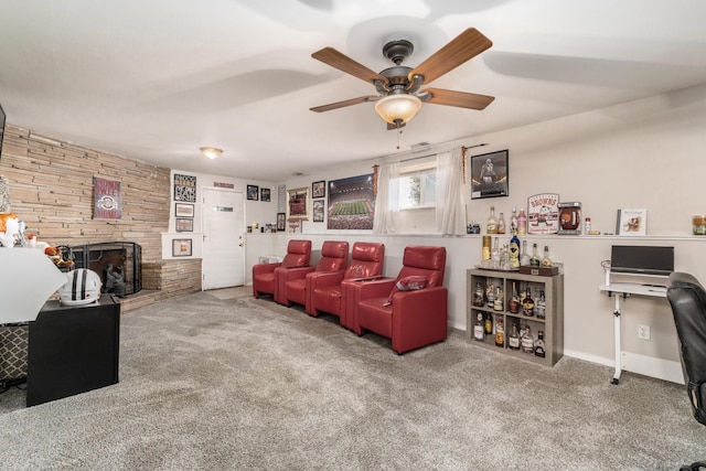 living area featuring carpet flooring, ceiling fan, and a stone fireplace