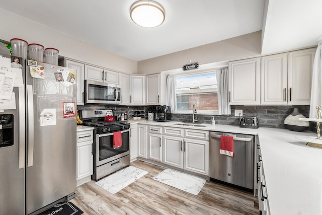 kitchen with stainless steel appliances, tasteful backsplash, light countertops, white cabinetry, and a sink