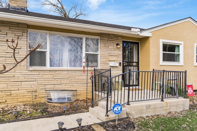 entrance to property featuring stone siding and stucco siding