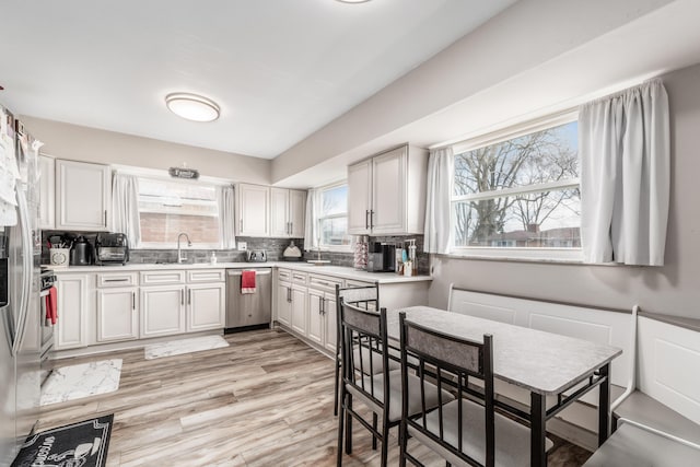 kitchen featuring tasteful backsplash, white cabinets, light countertops, and stainless steel dishwasher