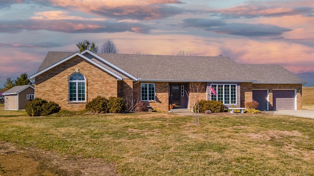 single story home with an attached garage, driveway, a front yard, and brick siding