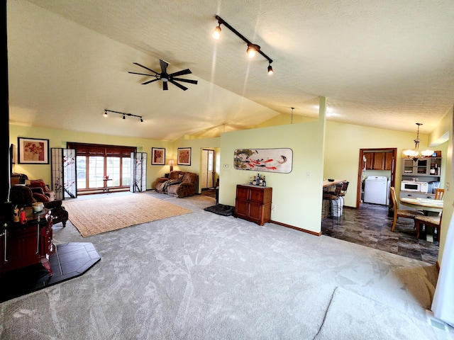 carpeted living room with vaulted ceiling, a textured ceiling, washer / dryer, baseboards, and ceiling fan with notable chandelier