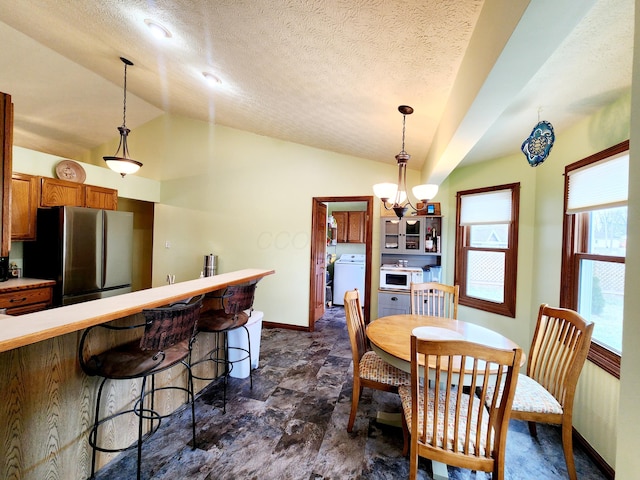 dining room featuring an inviting chandelier, baseboards, washer / clothes dryer, and vaulted ceiling