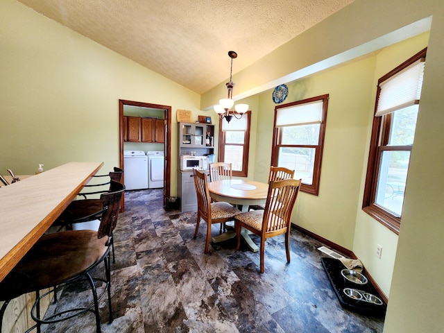 dining space featuring baseboards, lofted ceiling, independent washer and dryer, a textured ceiling, and a notable chandelier