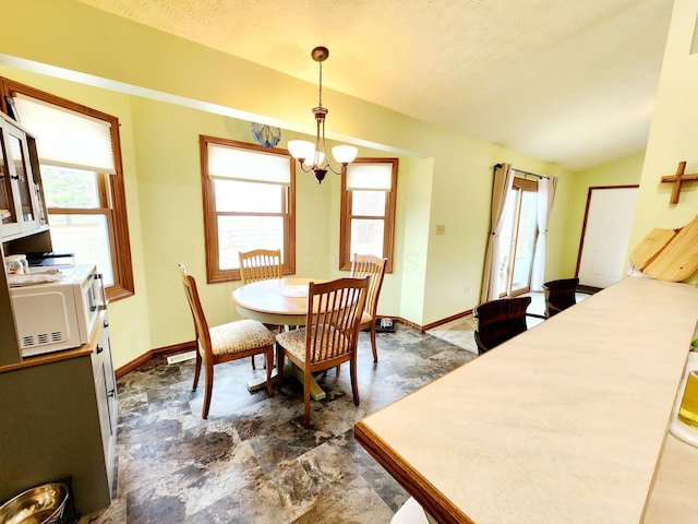 dining area featuring lofted ceiling, plenty of natural light, and baseboards