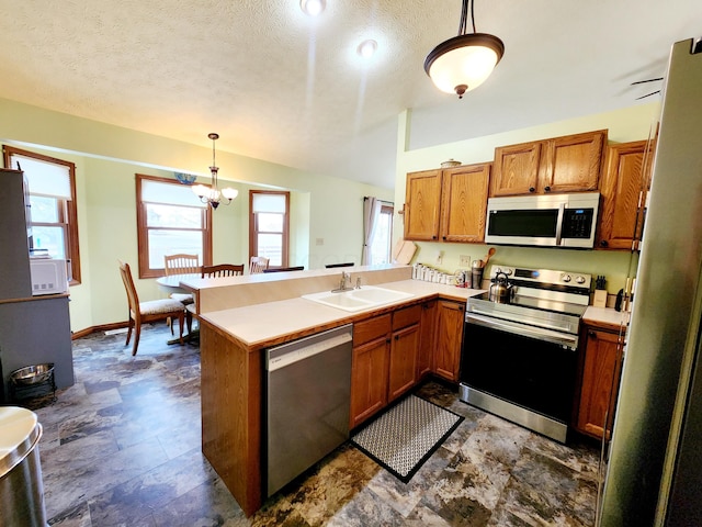 kitchen with brown cabinets, a peninsula, stainless steel appliances, light countertops, and a sink