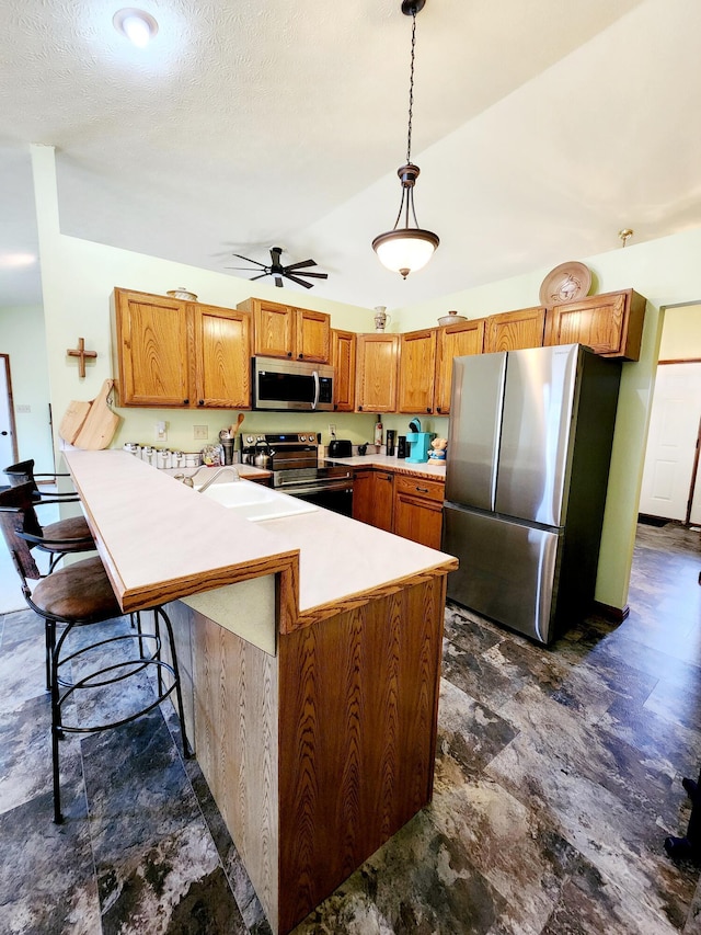 kitchen with brown cabinets, a kitchen breakfast bar, stainless steel appliances, light countertops, and pendant lighting