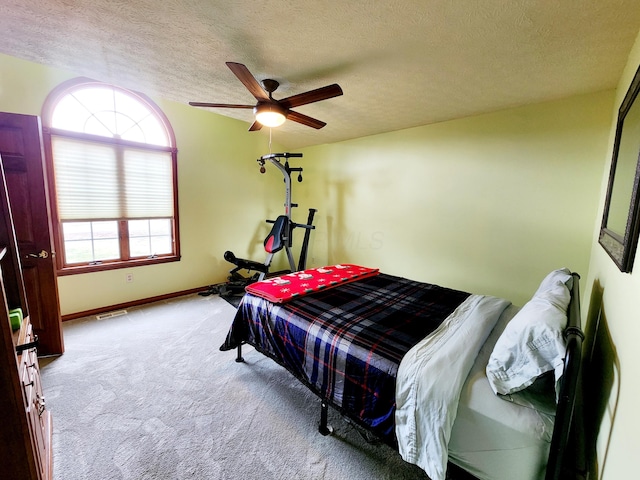 bedroom featuring a textured ceiling, ceiling fan, carpet flooring, visible vents, and baseboards