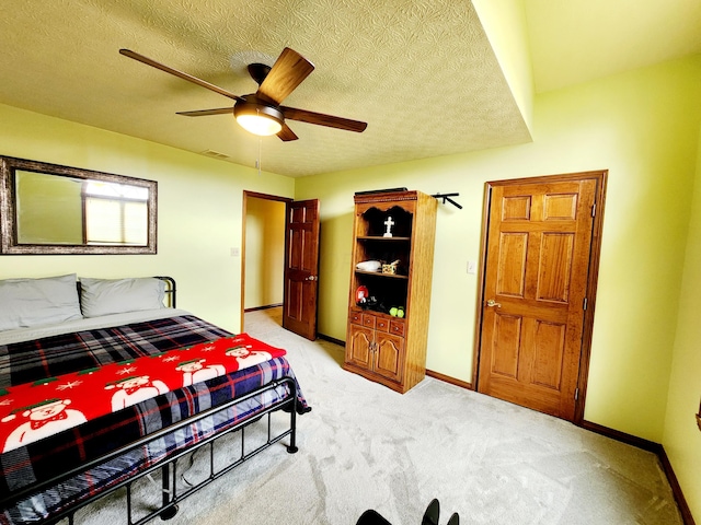 bedroom with light carpet, visible vents, baseboards, a ceiling fan, and a textured ceiling