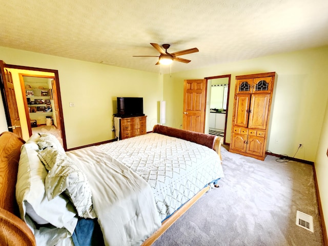 bedroom with a textured ceiling, light carpet, visible vents, and baseboards