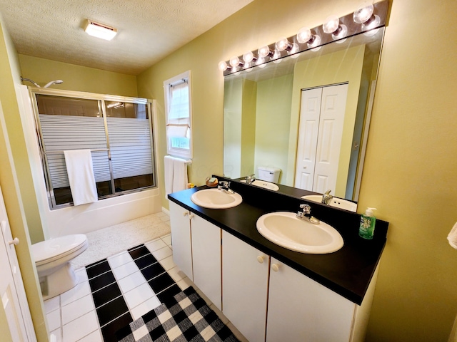 full bathroom featuring a sink, a textured ceiling, toilet, and double vanity