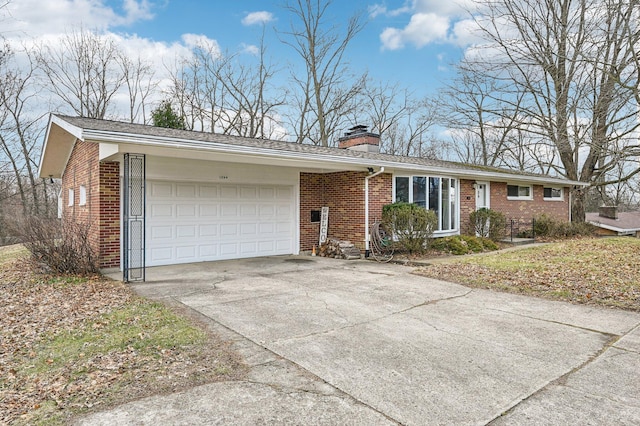 single story home featuring an attached garage, a chimney, concrete driveway, and brick siding