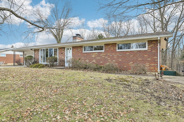 ranch-style house featuring brick siding, a chimney, and a front yard