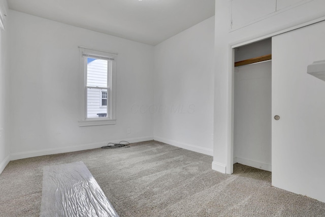 unfurnished bedroom featuring carpet floors, baseboards, and a closet