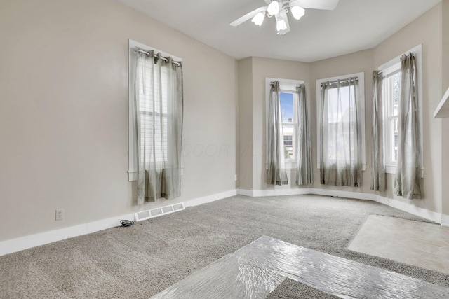 carpeted empty room featuring ceiling fan, visible vents, and baseboards