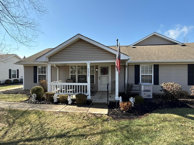 ranch-style house with covered porch, a shingled roof, and a front yard