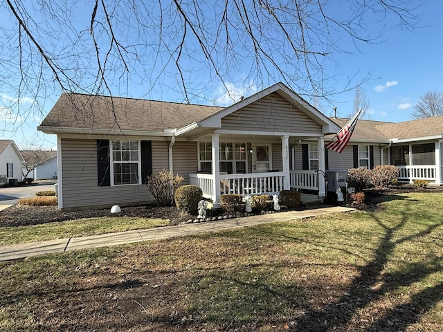 view of front facade with covered porch, a front lawn, and a shingled roof