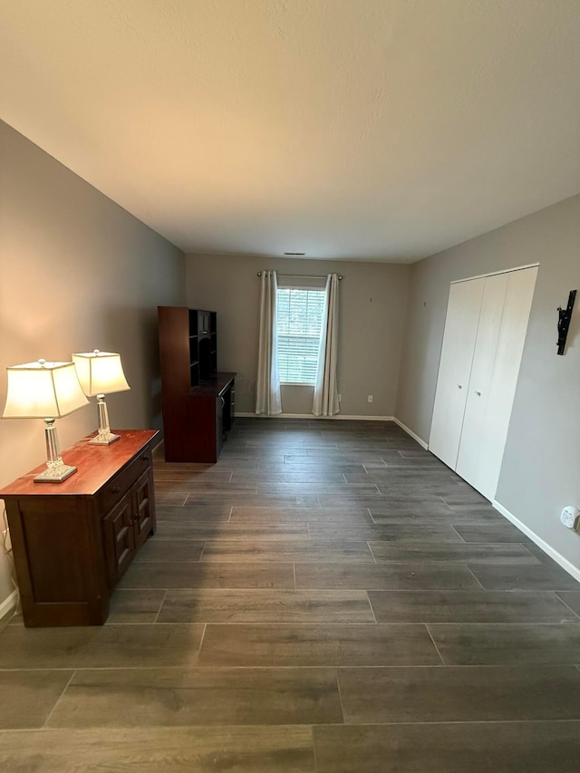 unfurnished bedroom with dark wood finished floors and baseboards