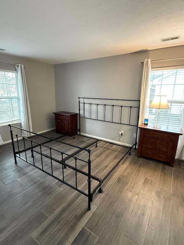 bedroom with visible vents, baseboards, and wood finished floors