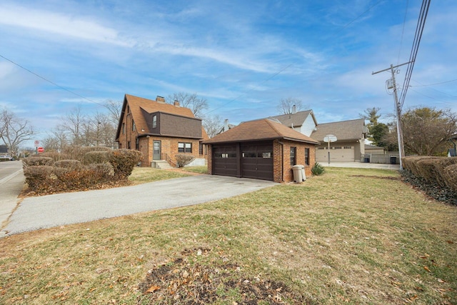 view of front facade featuring a garage, brick siding, a front lawn, and an outbuilding