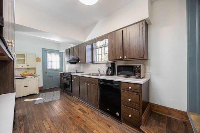 kitchen featuring under cabinet range hood, a sink, dark brown cabinets, black appliances, and dark wood finished floors